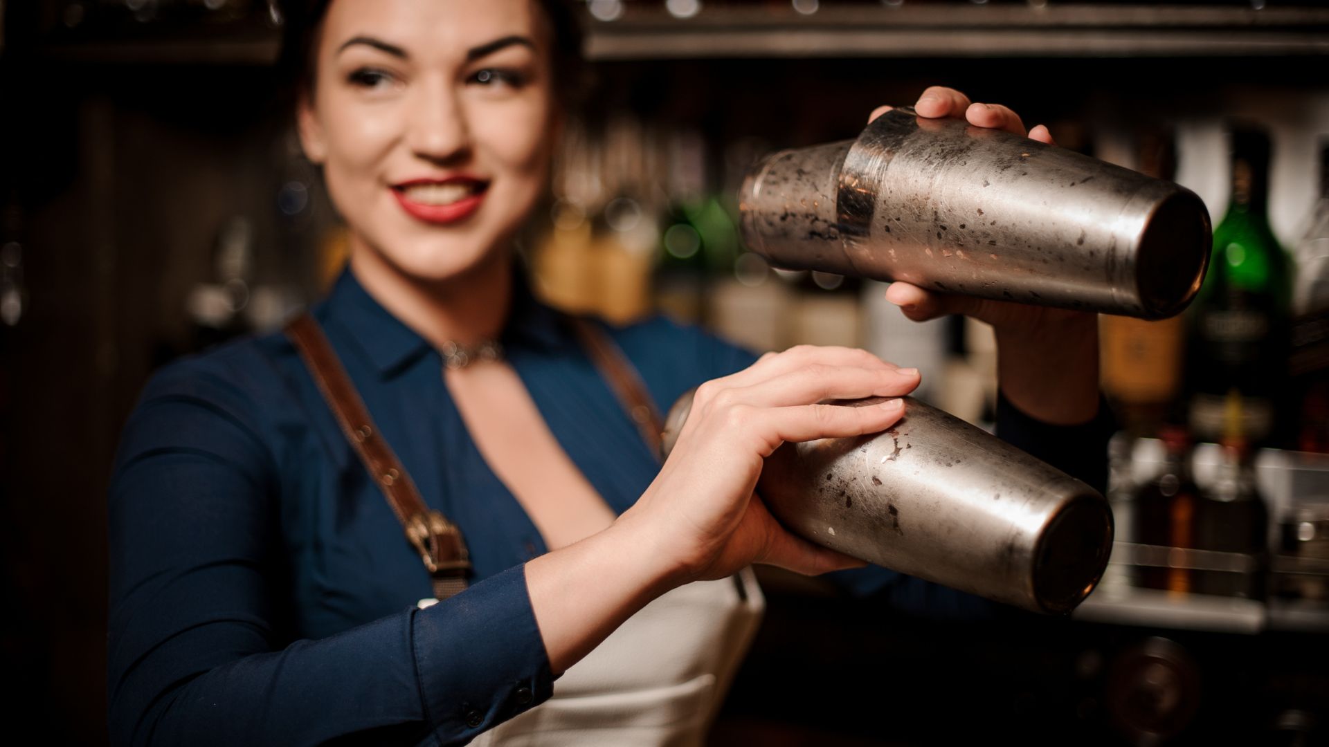 A woman is holding a cocktail shaker in her hand